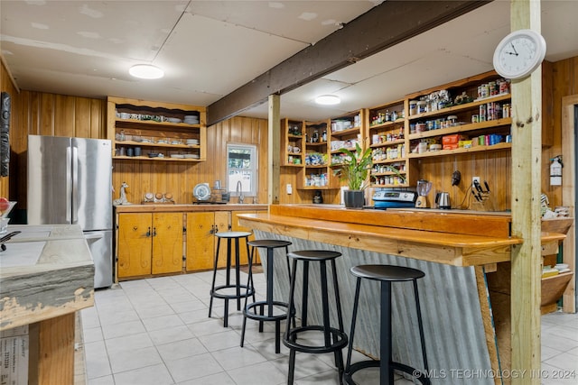 bar with light tile patterned flooring, wood walls, and stainless steel appliances