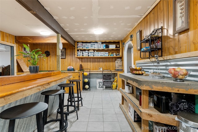 bar with wood counters, light tile patterned floors, and wooden walls