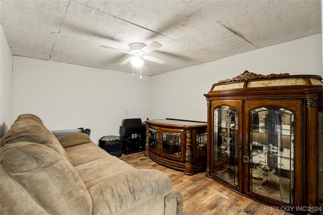 living room featuring light hardwood / wood-style flooring, a textured ceiling, and ceiling fan