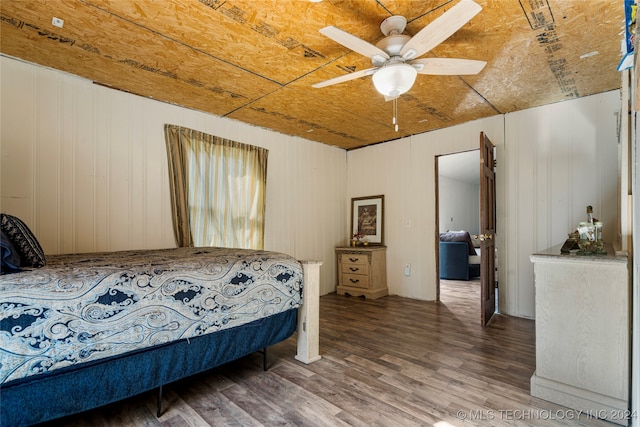 bedroom featuring wood walls, hardwood / wood-style floors, and ceiling fan