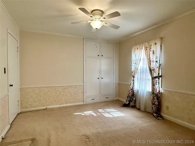 unfurnished bedroom featuring ceiling fan, light carpet, and ornamental molding