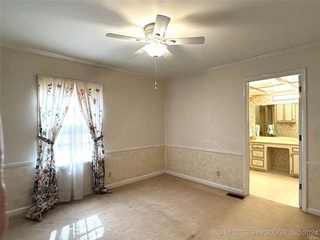 spare room with crown molding, light colored carpet, and ceiling fan