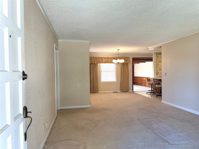 unfurnished room with light carpet, crown molding, a textured ceiling, and a notable chandelier