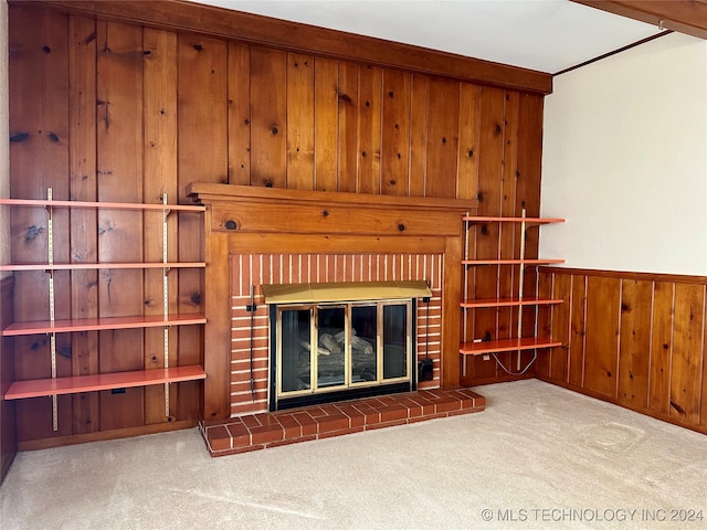 unfurnished living room with wooden walls, a brick fireplace, and light carpet