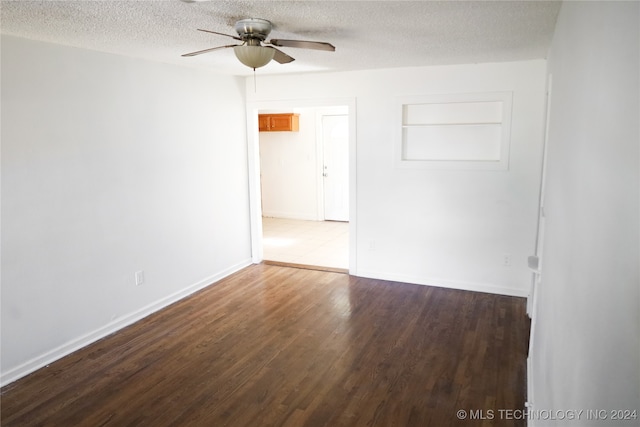 spare room with dark hardwood / wood-style floors, a textured ceiling, built in features, and ceiling fan