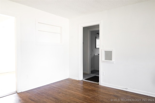 spare room with a textured ceiling and dark hardwood / wood-style floors