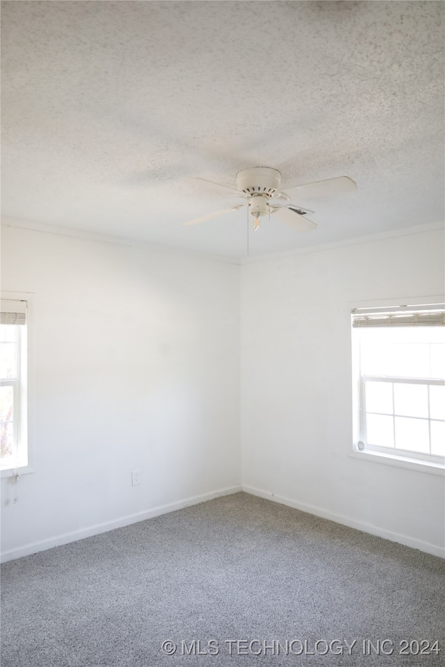 carpeted spare room featuring a textured ceiling and ceiling fan