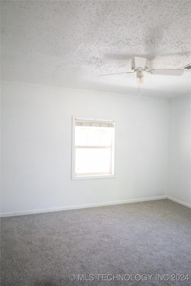 carpeted spare room with ceiling fan and a textured ceiling