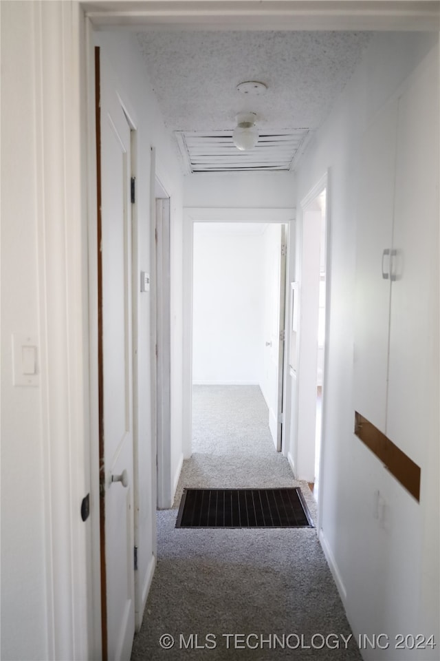 corridor with a textured ceiling and carpet