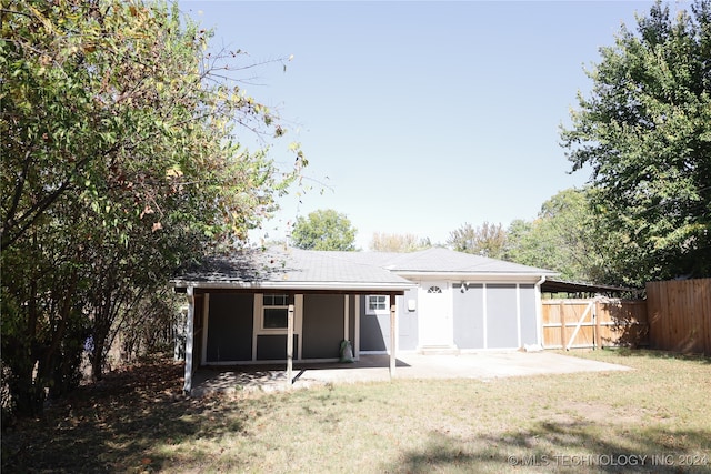 rear view of house with a patio area, a sunroom, and a lawn