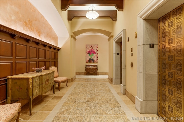 interior space with beamed ceiling, decorative columns, a towering ceiling, and light tile patterned floors