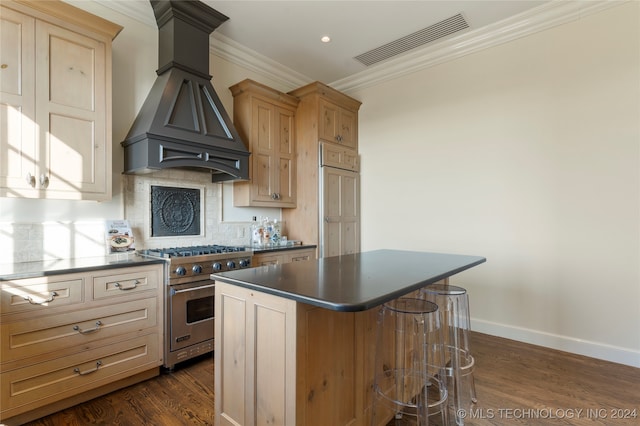 kitchen with dark hardwood / wood-style flooring, a kitchen island, premium range hood, crown molding, and luxury range