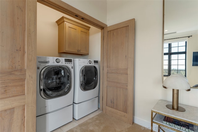 laundry area featuring washer and dryer, light tile patterned floors, and cabinets