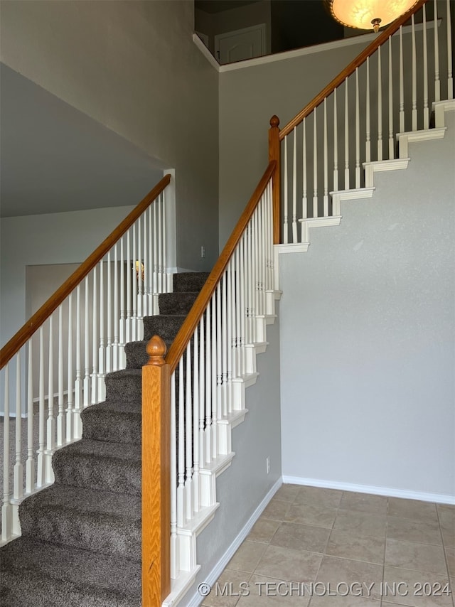 stairs with tile patterned floors and a high ceiling