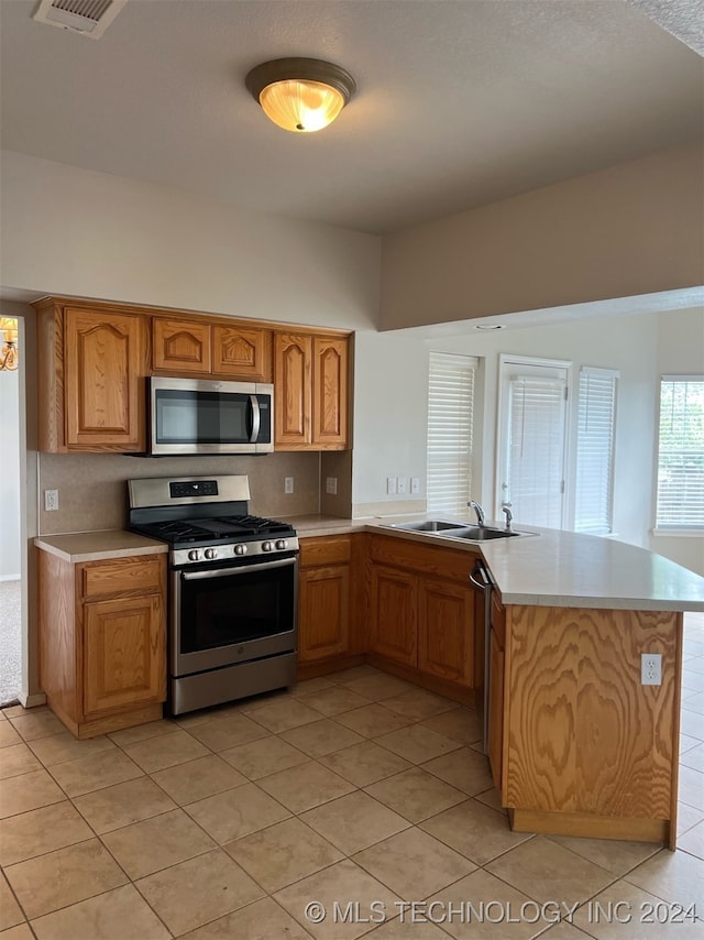 kitchen with stainless steel appliances, sink, kitchen peninsula, and light tile patterned flooring