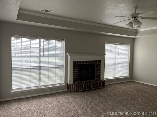 unfurnished living room featuring a wealth of natural light, ornamental molding, carpet, and a brick fireplace