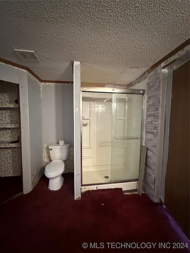 bathroom with a textured ceiling, toilet, and walk in shower