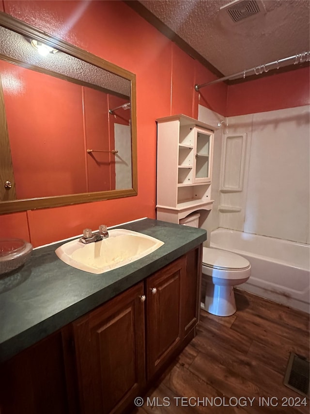 full bathroom featuring hardwood / wood-style flooring, toilet,  shower combination, vanity, and a textured ceiling