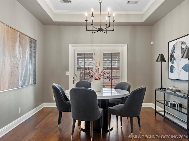 dining room featuring crown molding, a notable chandelier, a raised ceiling, and dark hardwood / wood-style flooring