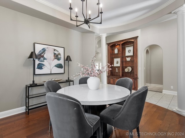 dining room with crown molding, hardwood / wood-style flooring, a notable chandelier, and decorative columns