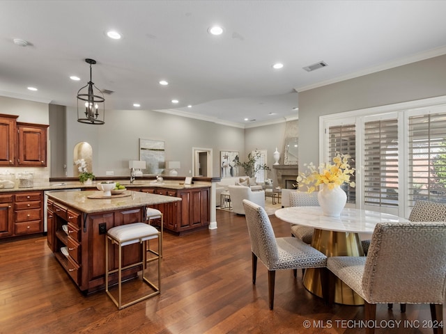 kitchen featuring a kitchen bar, a fireplace, a center island, a chandelier, and dark hardwood / wood-style floors