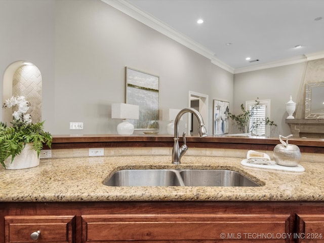 kitchen with crown molding, sink, and light stone counters