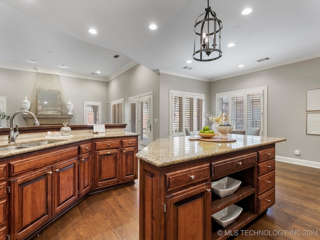 kitchen featuring sink, a center island, decorative light fixtures, ornamental molding, and dark hardwood / wood-style floors