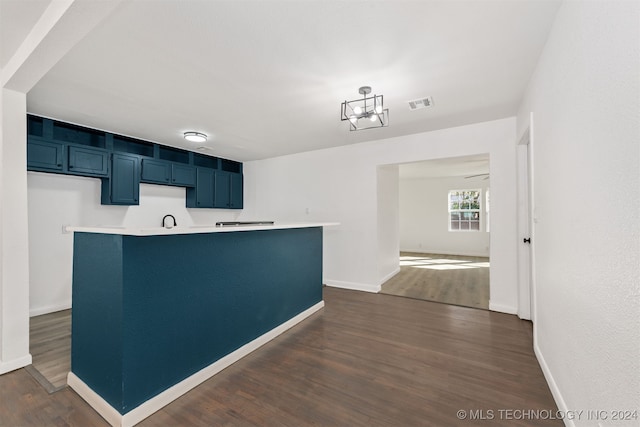 kitchen featuring a notable chandelier, dark hardwood / wood-style floors, blue cabinets, and a kitchen island