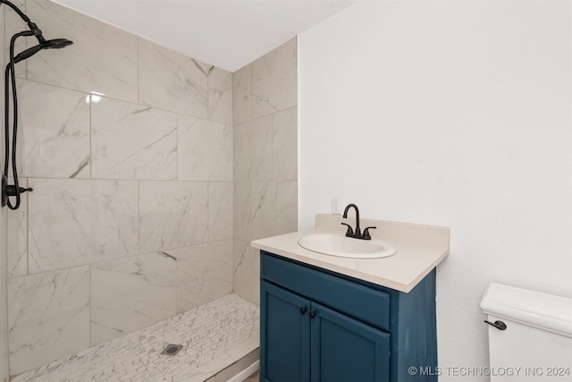 bathroom featuring vanity, toilet, and tiled shower