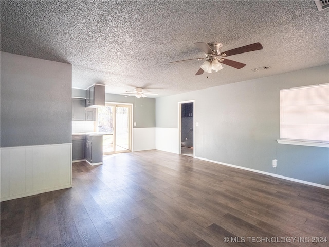 unfurnished living room with ceiling fan, dark hardwood / wood-style flooring, and a textured ceiling