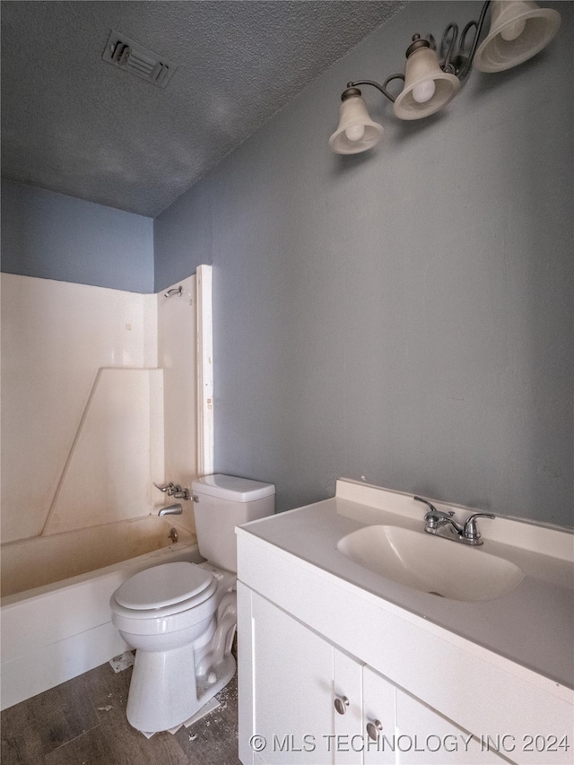 full bathroom with hardwood / wood-style floors, vanity, shower / tub combination, toilet, and a textured ceiling