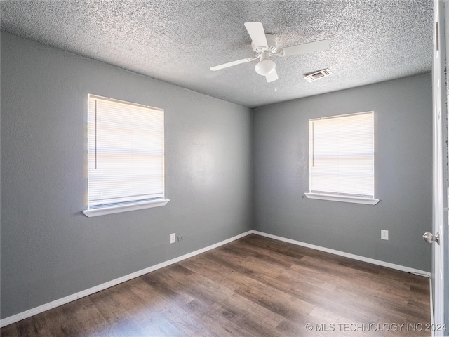 unfurnished room with ceiling fan, dark hardwood / wood-style flooring, and a textured ceiling