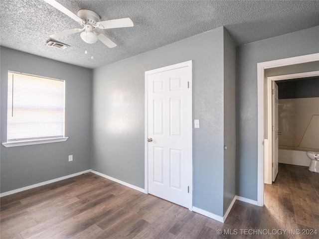 unfurnished bedroom with ceiling fan, dark hardwood / wood-style flooring, and a textured ceiling