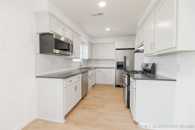 kitchen featuring sink, light wood-type flooring, white cabinetry, stainless steel appliances, and decorative backsplash