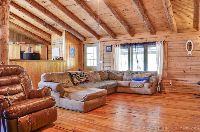 living room with lofted ceiling with beams, a healthy amount of sunlight, light wood-type flooring, and wooden walls