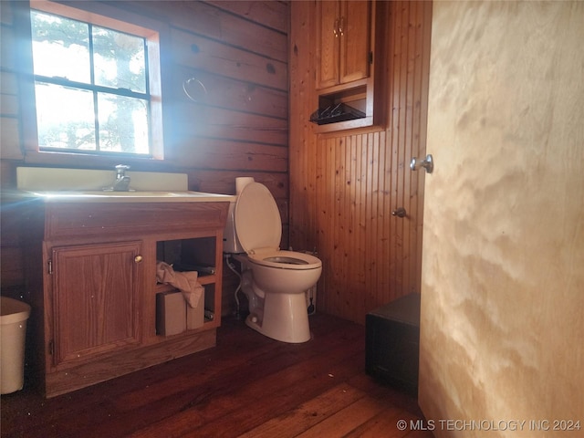 bathroom with hardwood / wood-style flooring, vanity, toilet, and wooden walls