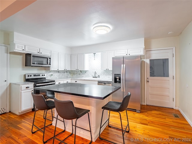 kitchen featuring a breakfast bar, white cabinetry, light hardwood / wood-style flooring, sink, and stainless steel appliances