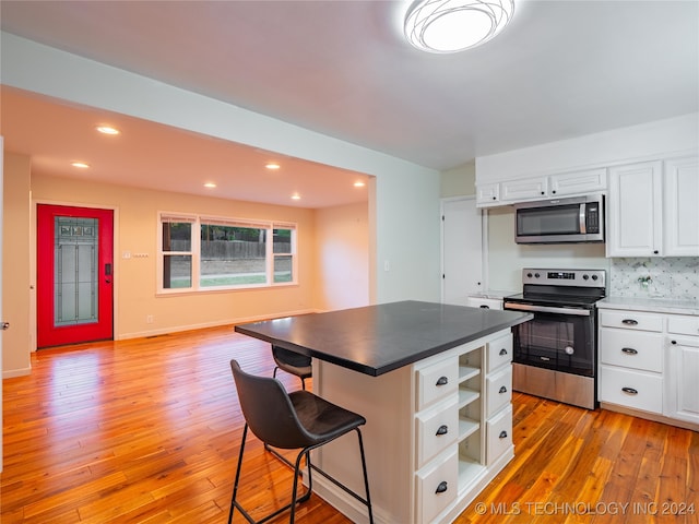 kitchen with a center island, white cabinets, stainless steel appliances, and light wood-type flooring