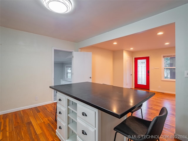 kitchen featuring hardwood / wood-style flooring, a breakfast bar area, and white cabinets