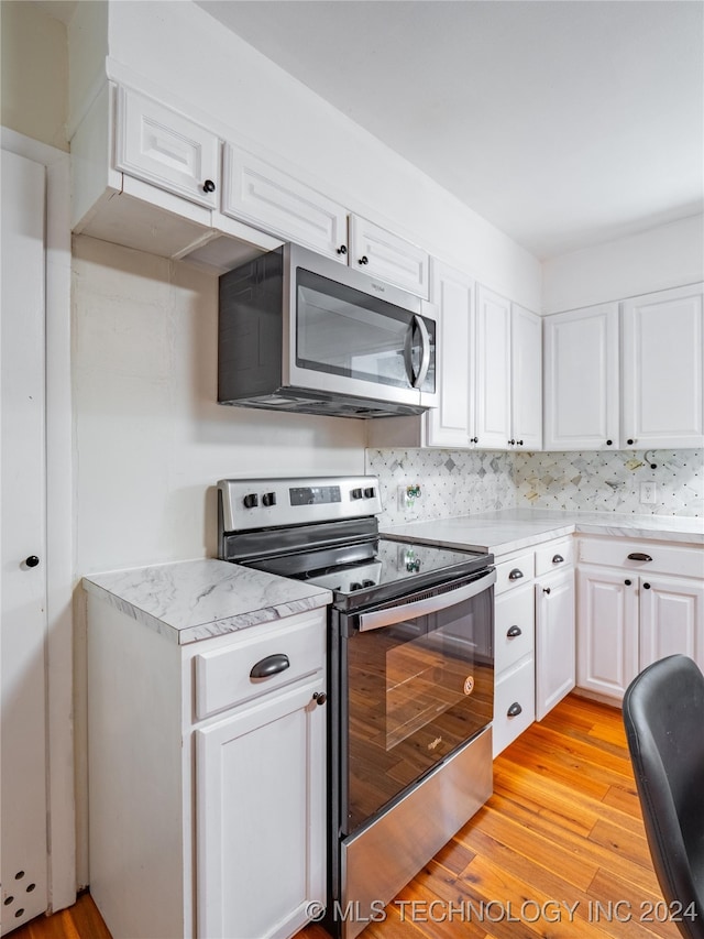 kitchen with decorative backsplash, appliances with stainless steel finishes, white cabinetry, and light hardwood / wood-style floors