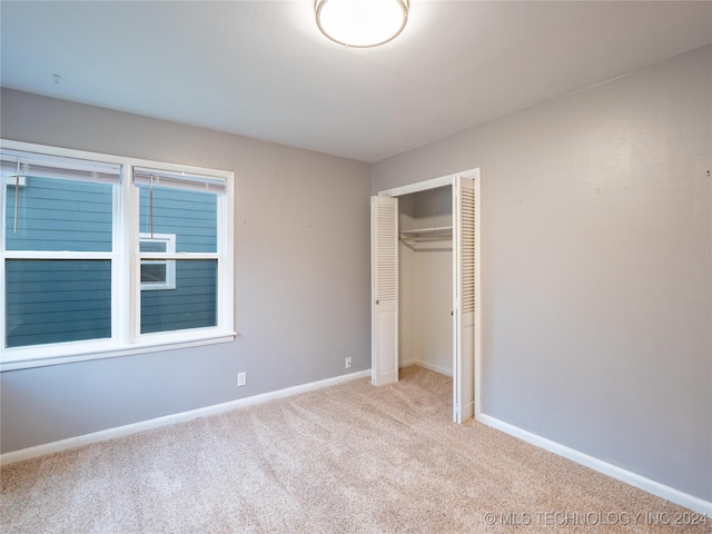 unfurnished bedroom with a closet and light carpet