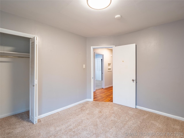 unfurnished bedroom featuring a closet and light colored carpet