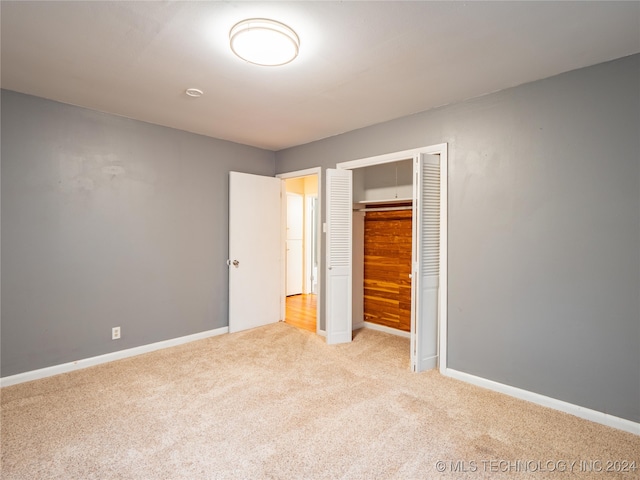 unfurnished bedroom featuring a closet and light carpet