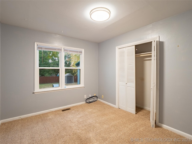 unfurnished bedroom with a closet and light colored carpet