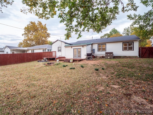 rear view of property with a wooden deck, cooling unit, and a yard