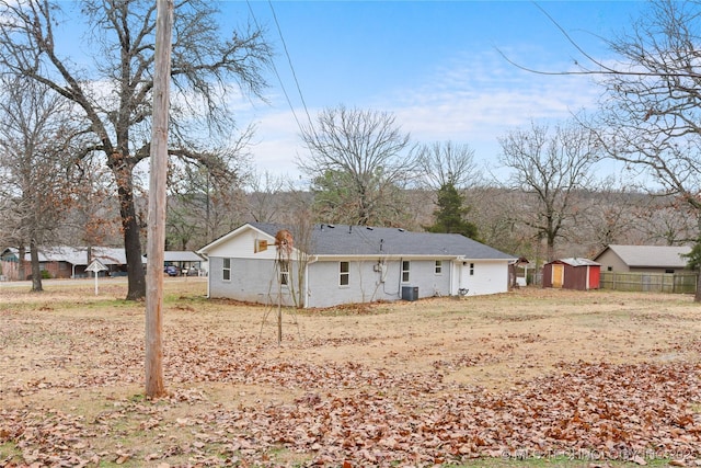 back of property with central AC unit and a storage unit