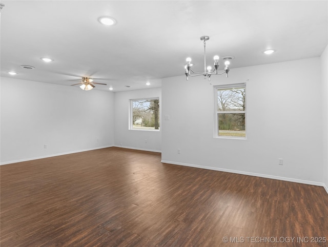 empty room featuring dark hardwood / wood-style flooring, plenty of natural light, and ceiling fan with notable chandelier