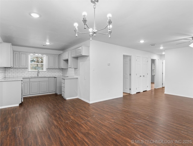 kitchen with ceiling fan with notable chandelier, decorative backsplash, sink, dark hardwood / wood-style floors, and gray cabinetry