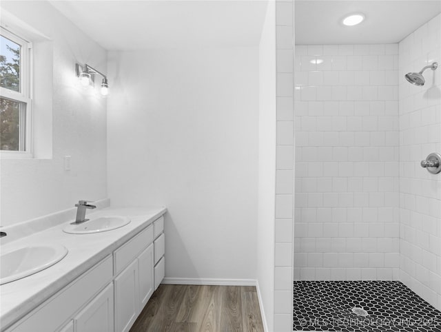 bathroom with tiled shower, hardwood / wood-style floors, and vanity