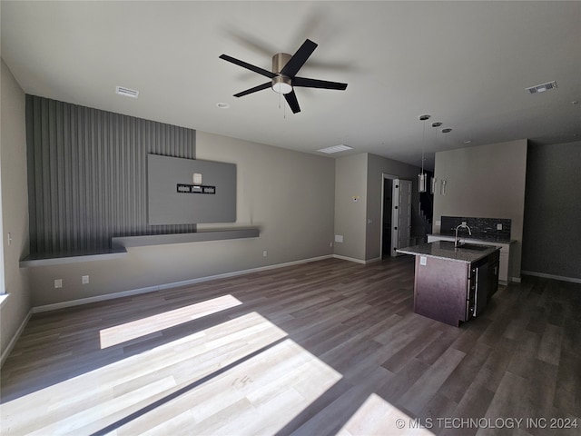 kitchen featuring sink, an island with sink, hanging light fixtures, ceiling fan, and dark wood-type flooring